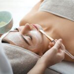 Frau liegt mit aufgetragener Gesichtsmaske auf der Liege – Vorbereitung zur Hydrafacial Behandlung